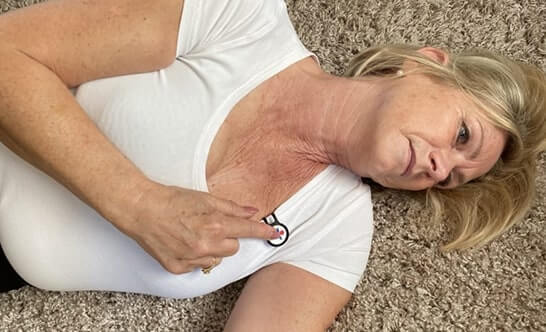 A person on a soft surface, pushing a small wearable Flic safety button.
