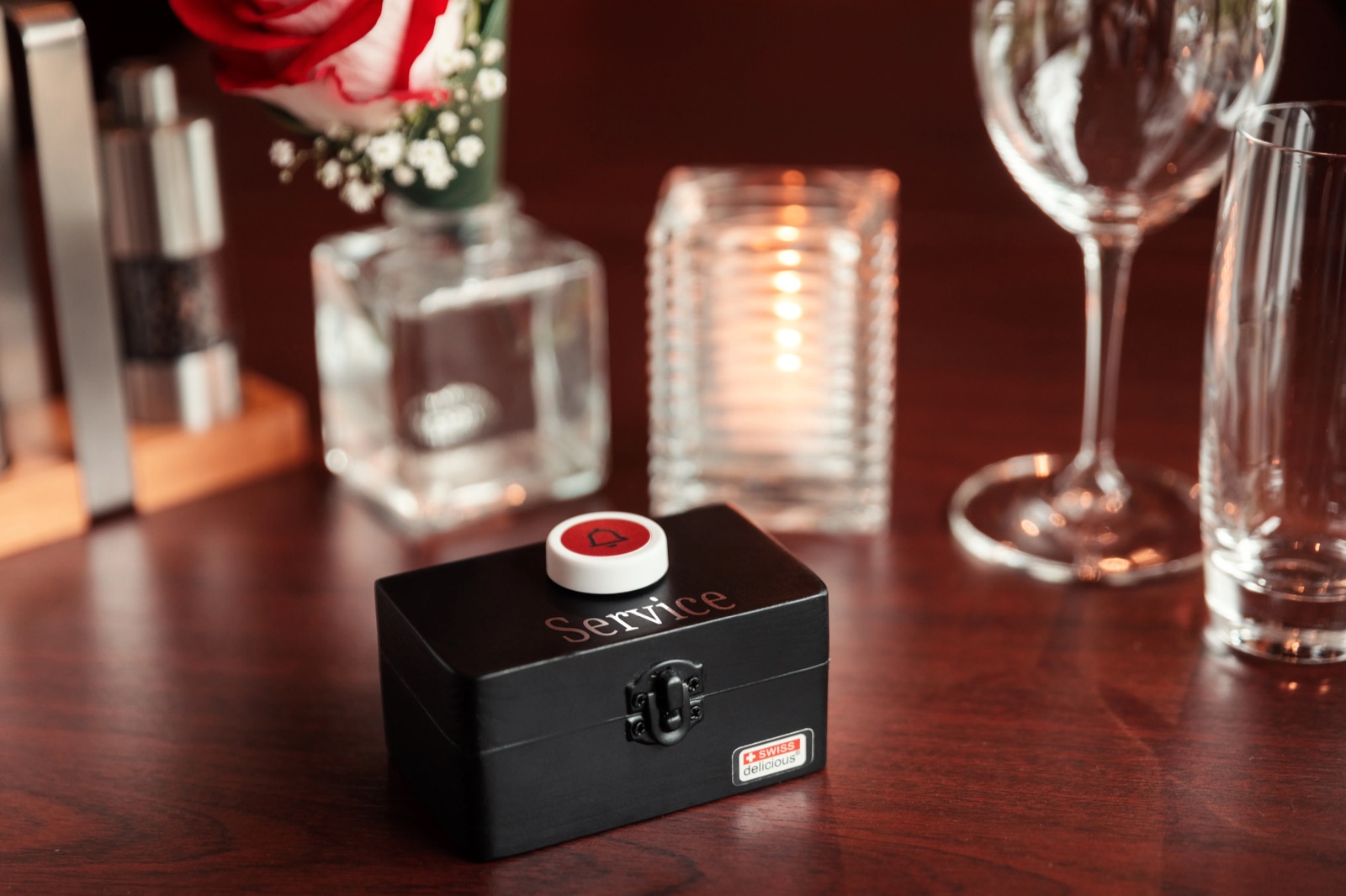 A red Flic service button mounted on a small black box at a fine-dining restaurant table.